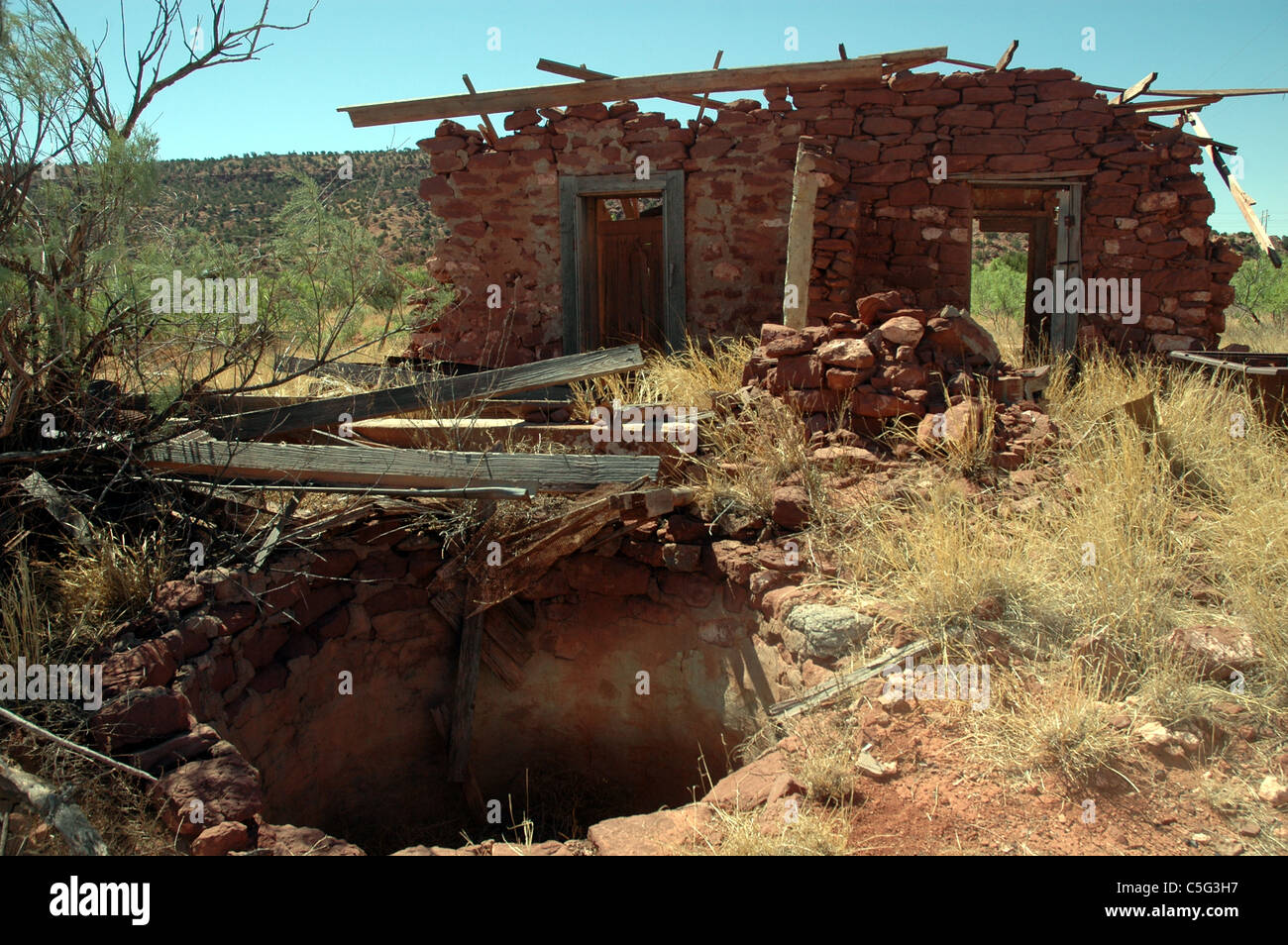 Un antico pozzo si trova nel cortile anteriore di una casa di campagna in un avanzato stato di decadenza. Foto Stock