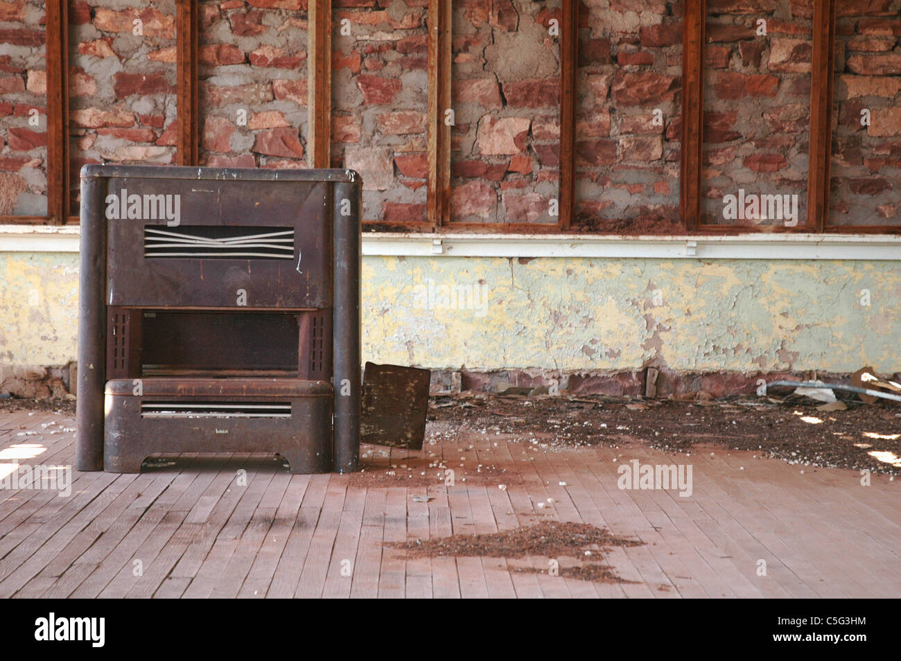 Una vecchia stufa si siede di fronte a una rottura scheda di gesso in una scuola fatiscente casa in Cuervo Nuovo Messico città fantasma. Foto Stock