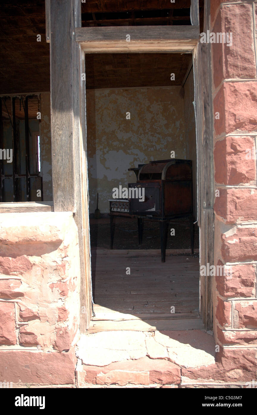 Una vecchia stufa può essere visto attraverso la porta dell'abbandonato schoolhouse in Cuervo, Nuovo Messico. Foto Stock