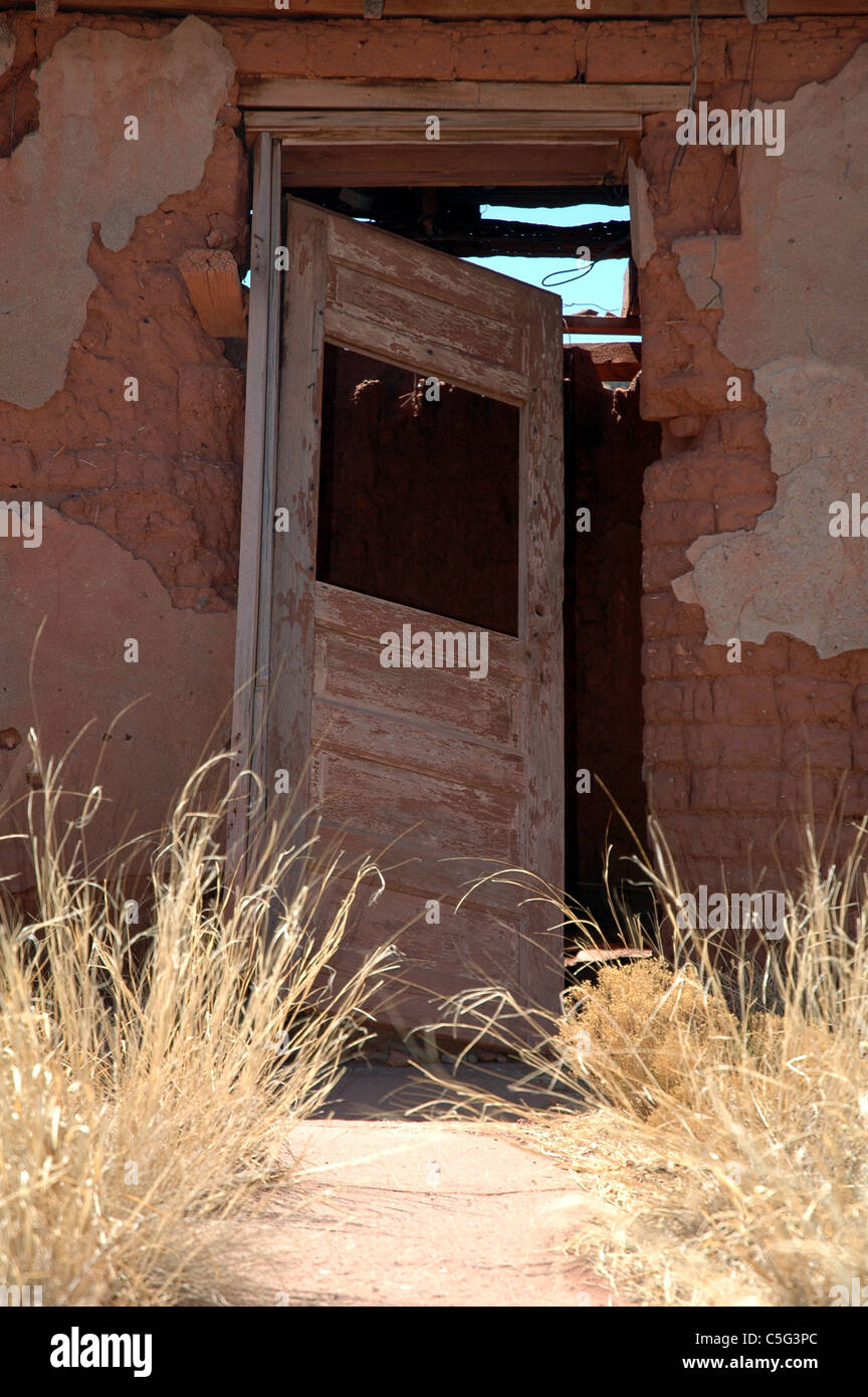 Erbacce soffocare la parte anteriore a piedi a lungo abbandonato, decadendo farm house. Foto Stock
