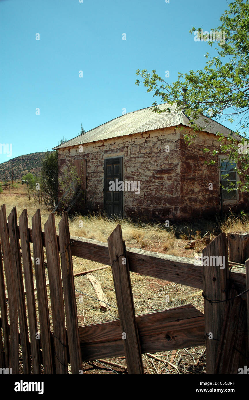 Un Picket Fence siede in stato di abbandono di fronte a un rock abbandonato casa in Cuervo New Mexico Foto Stock