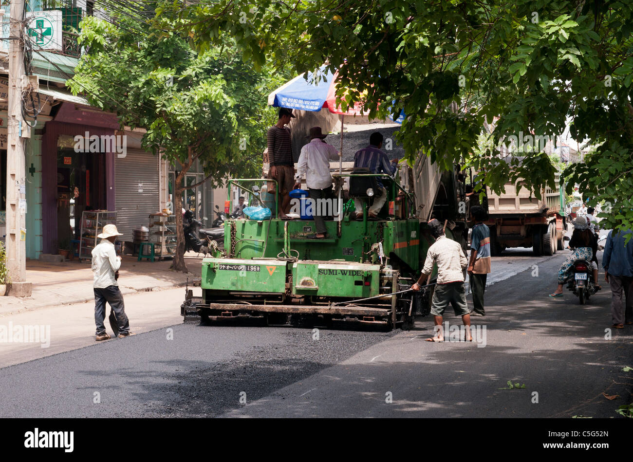 Strada pista lavoratori posa nuovo manto stradale in Somdech Tep Vong St, Siem Reap, Cambogia Foto Stock