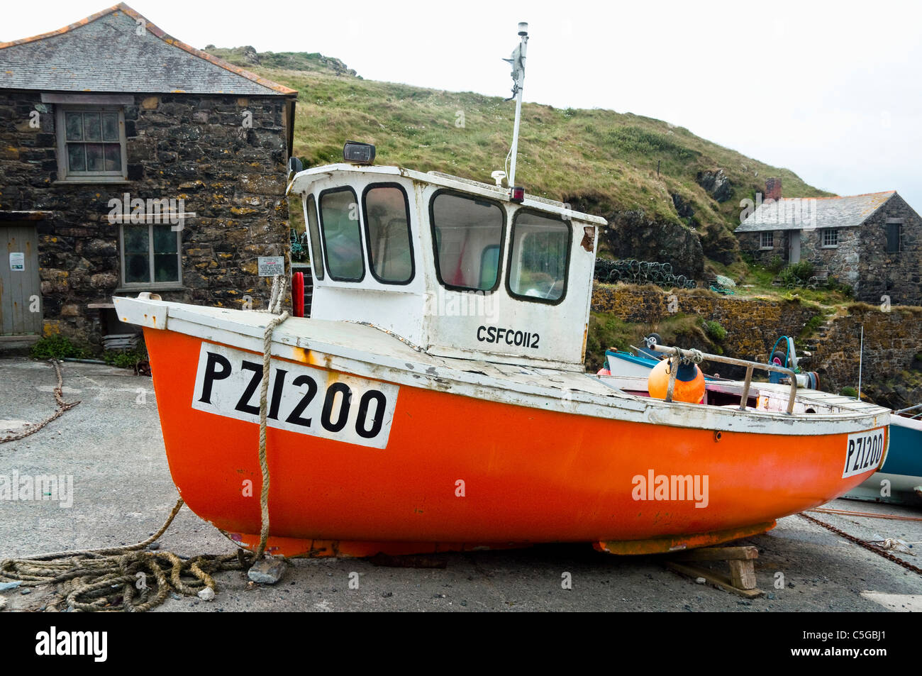 Arancio brillante del pescatore in barca la piccola pesca tradizionale del porto al Mullion Cove, Cornwall, Regno Unito. Foto Stock