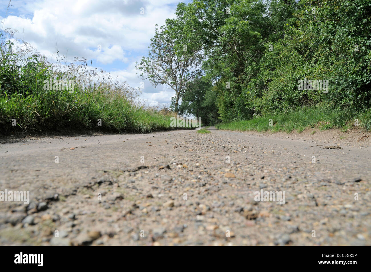 Basso livello vista su una tranquilla strada di campagna con l'erba che cresce in mezzo alla strada Foto Stock