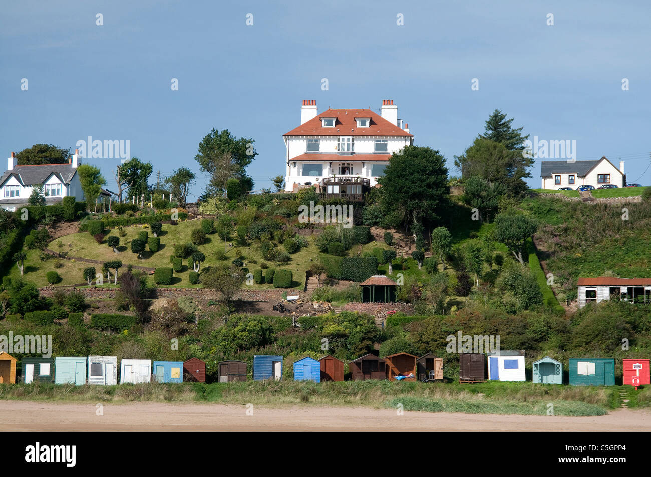 Coldingham Bay abitazioni private e giardini sulle rive della baia con spiaggia di capanne Foto Stock