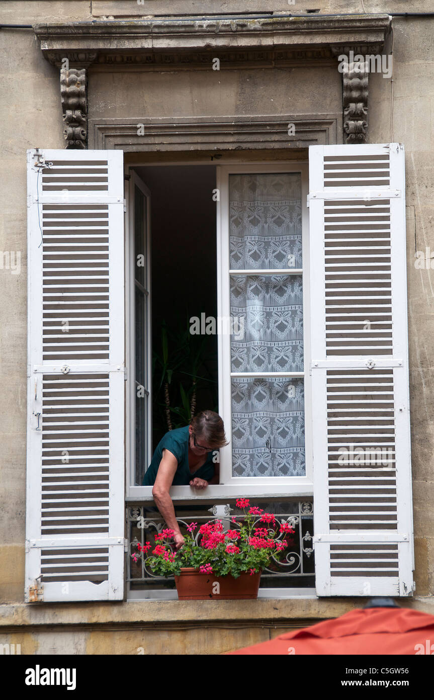 Donna che frequentano gerani in finestra ritagliata nel vecchio Bergerac Dordogne Aquitaine Francia Foto Stock