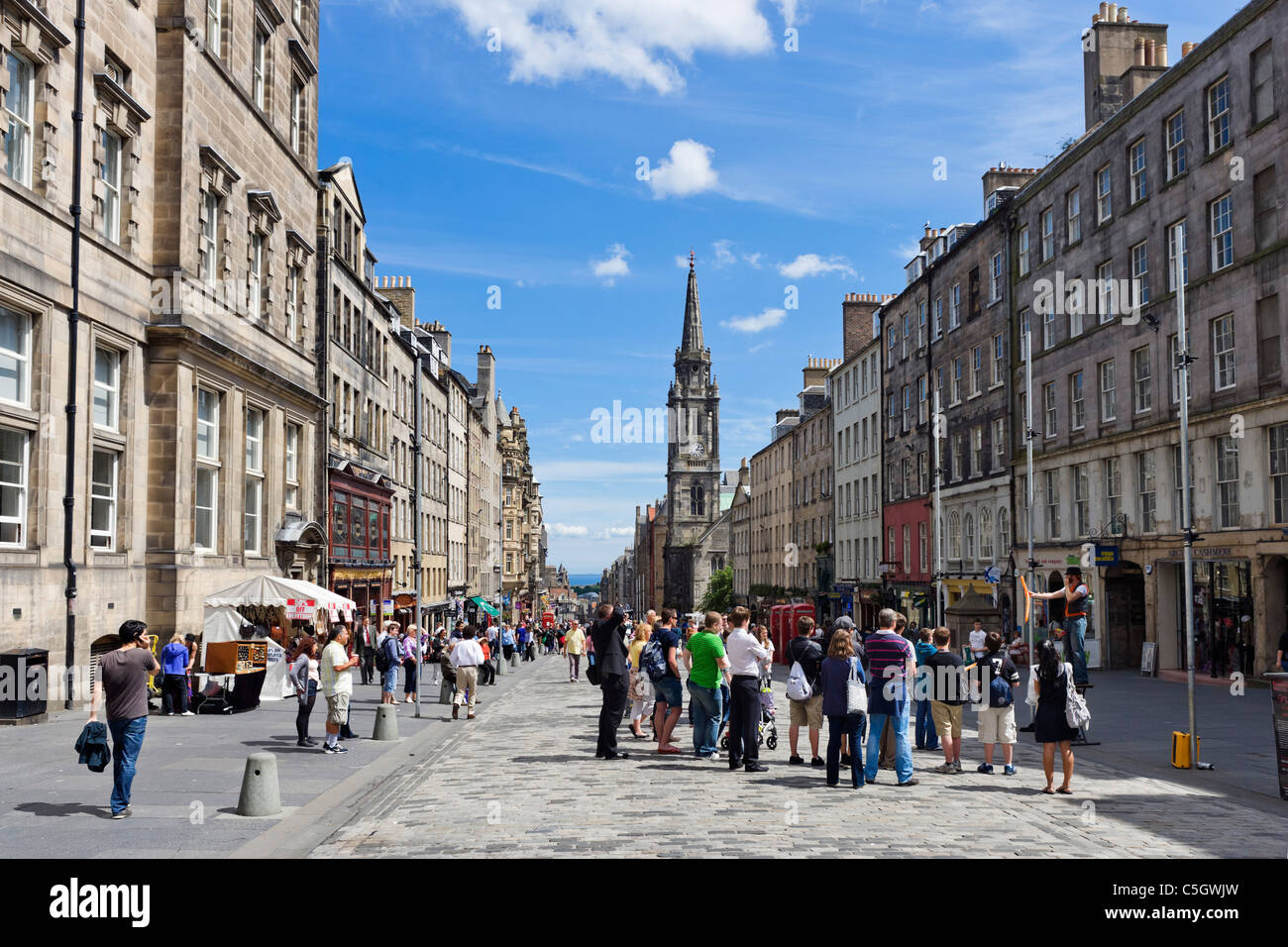 Negozi e animatore di strada sulla Strada Alta guardando verso Holyrood, Royal Mile di Edimburgo, Scozia, Regno Unito Foto Stock