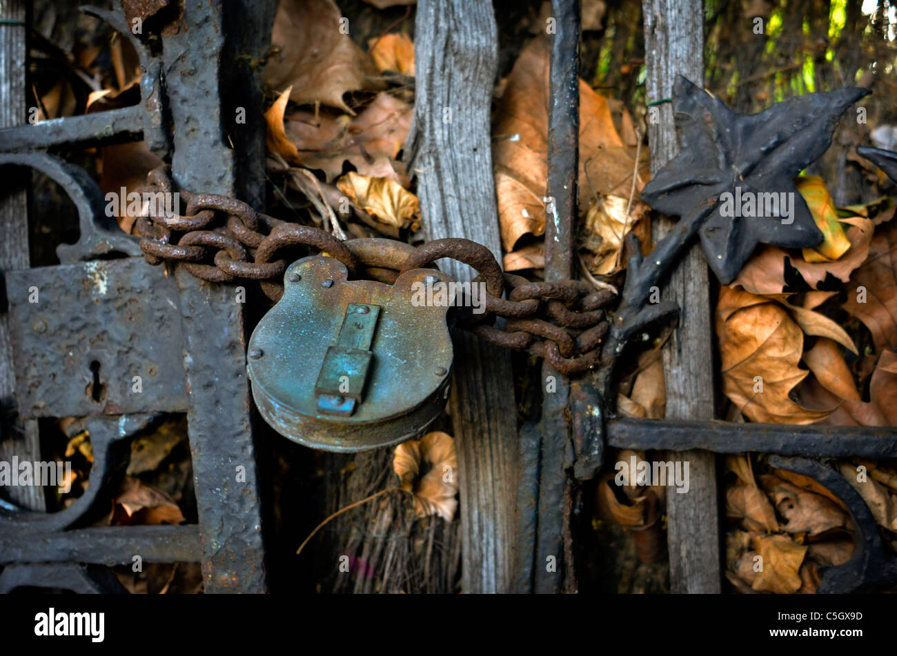 Antico cancello con lucchetto su una catena di ruggine Foto Stock