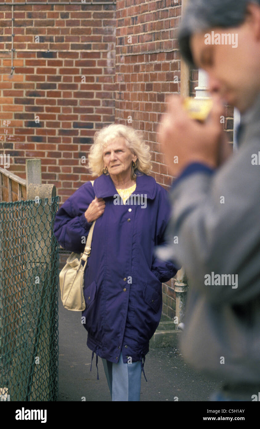 Donna anziana camminando lungo il vicolo passato suspcious cerca uomo che  si illumina di una sigaretta Foto stock - Alamy