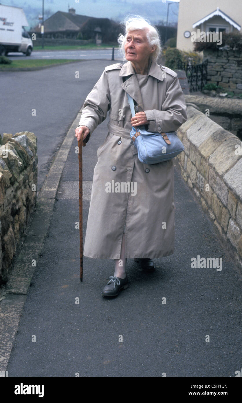 Signora anziana a piedi lungo la strada del villaggio Foto Stock