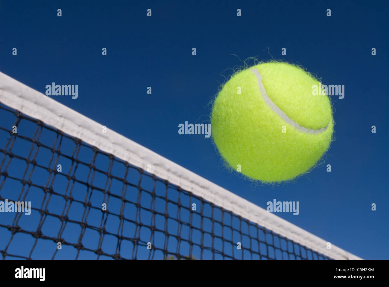 Un'immagine raffigurante il concetto di tennis, compresa una pallina di scorrimento sul net. Foto Stock