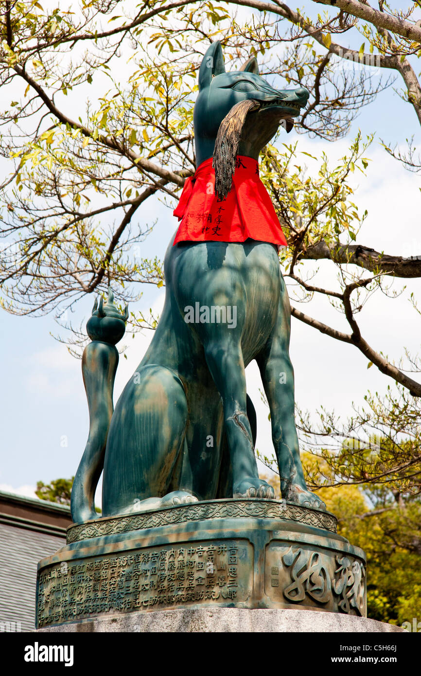 Statua di bronzo di un Kitsune, volpe, al santuario Inari a Fushimi a Kyoto. Considerato come un guardiano, ha un'offerta rossa e un taglio di riso in bocca. Foto Stock