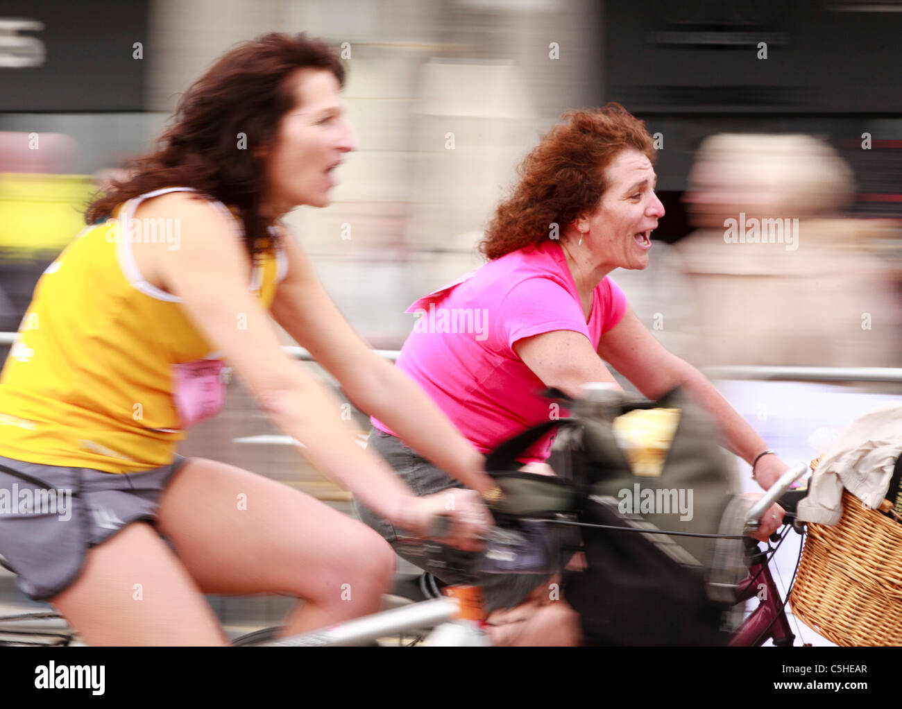 Due donne che si avvicinano alla linea di finitura della British Heart Foundation Londra a Brighton in bicicletta 2011 - sfocatura del movimento Foto Stock