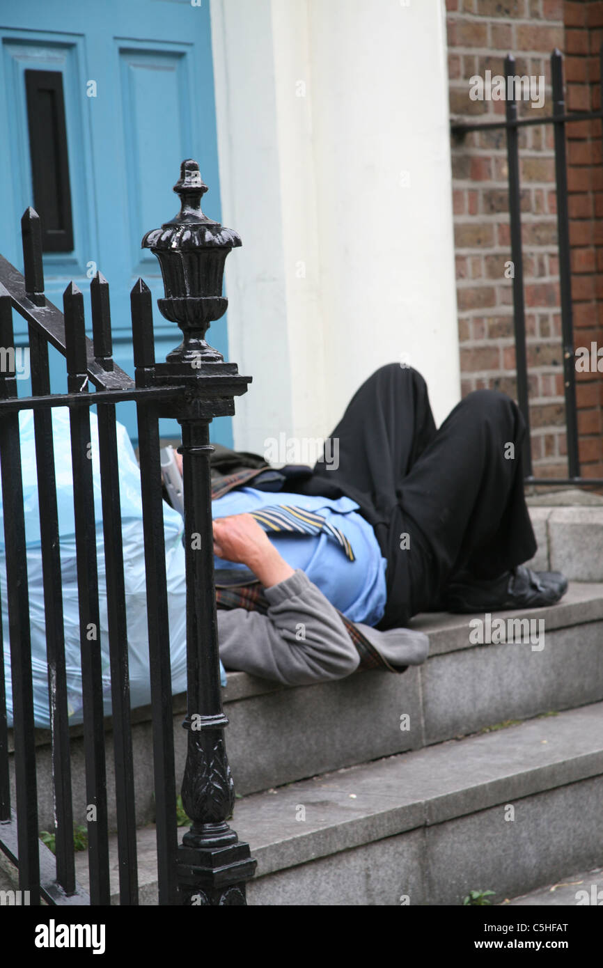 Senzatetto uomo disteso in una porta in ascolto della radio per le strade di Dublino in Irlanda Foto Stock