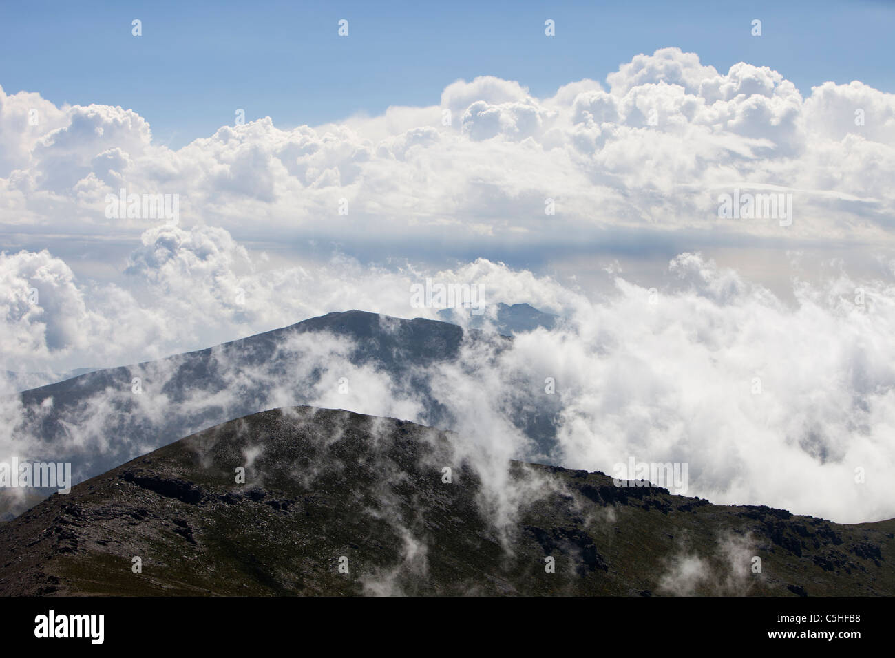 Le nuvole e la nebbia fino a gorgogliamento sopra le cime delle montagne della Sierra Nevada in Andalusia, Spagna Foto Stock