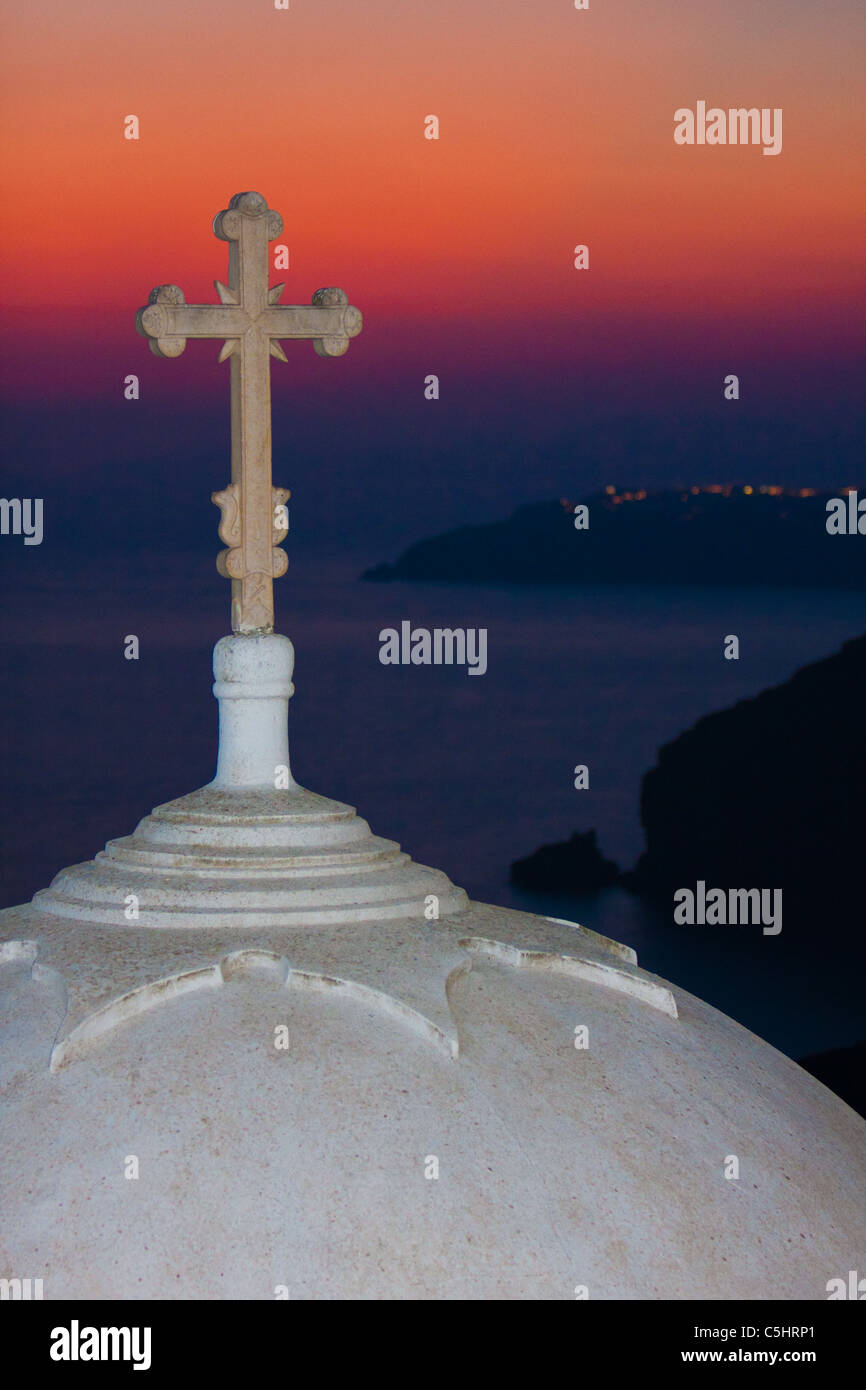 Chiesa bianca cupola con croce nel purpureo tramonto sull'oceano in Thera Foto Stock