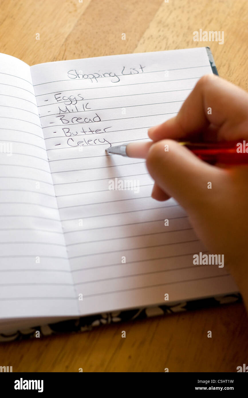La scrittura a mano fuori un negozio di generi alimentari shopping list con una penna e tampone. Foto Stock
