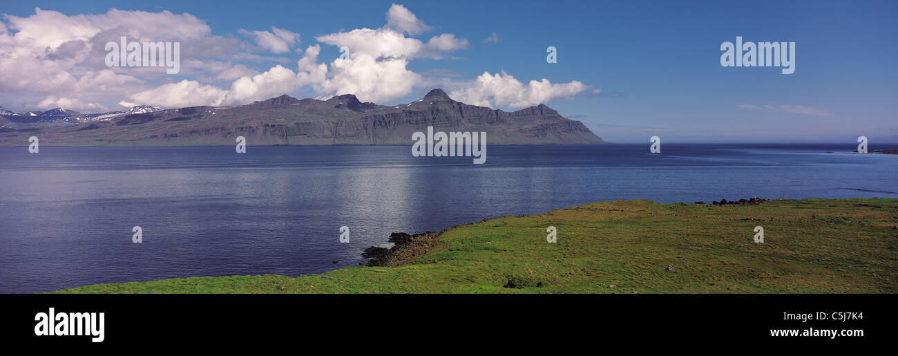 La capezzagna Krossanes visto attraverso un mare calmo in Reydarfjord, Est fiordi regione, Islanda. Foto Stock