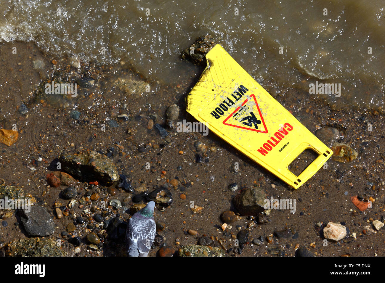 Attenzione pavimento bagnato segno essendo lavato fino dal fiume Tamigi, Londra, Inghilterra Foto Stock