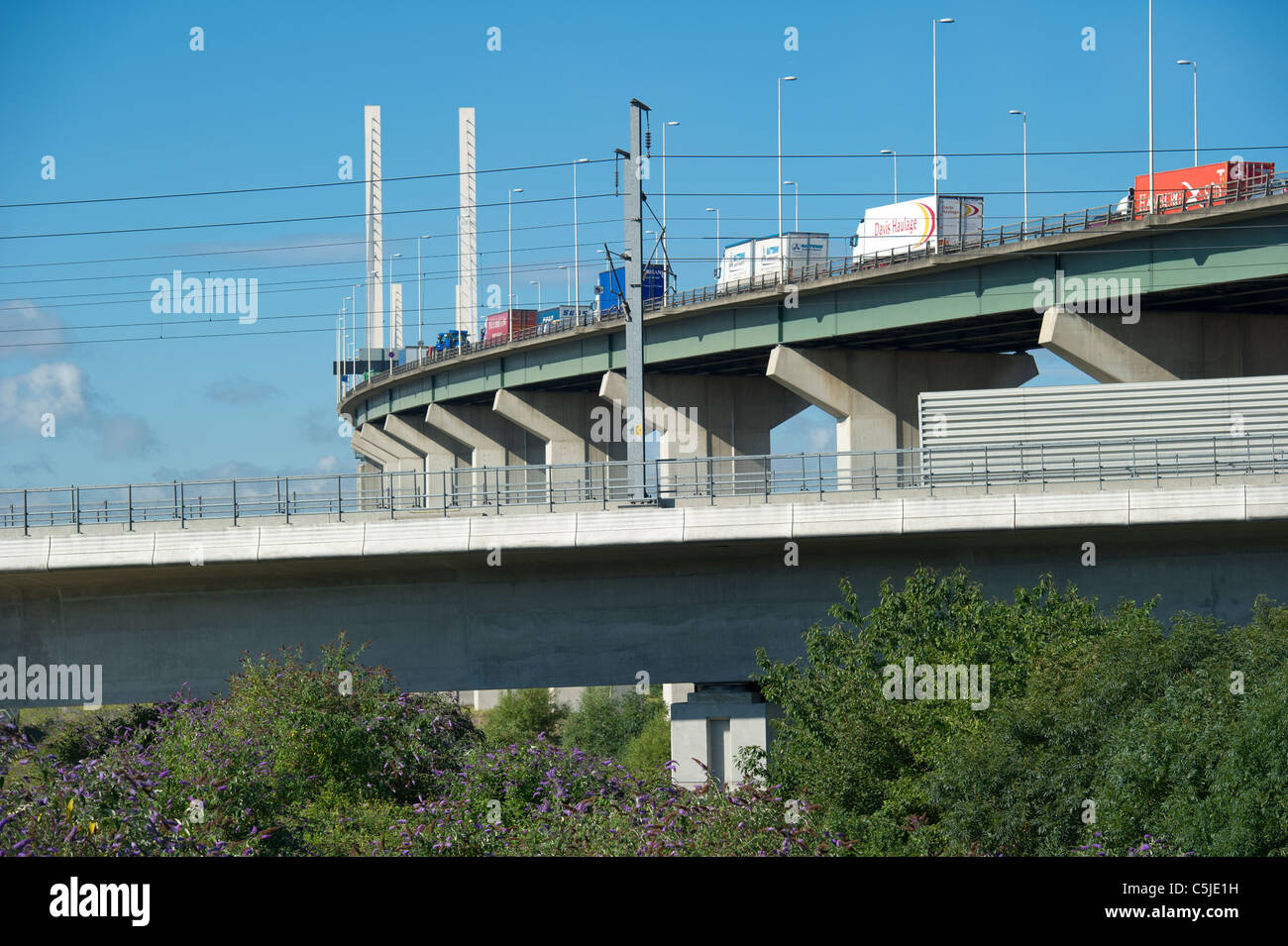 Una linea di veicoli pesanti per trasporto merci fanno il loro cammino oltre il Dartford Crossing in Kent con Eurostar via mostrato in primo piano. Foto Stock