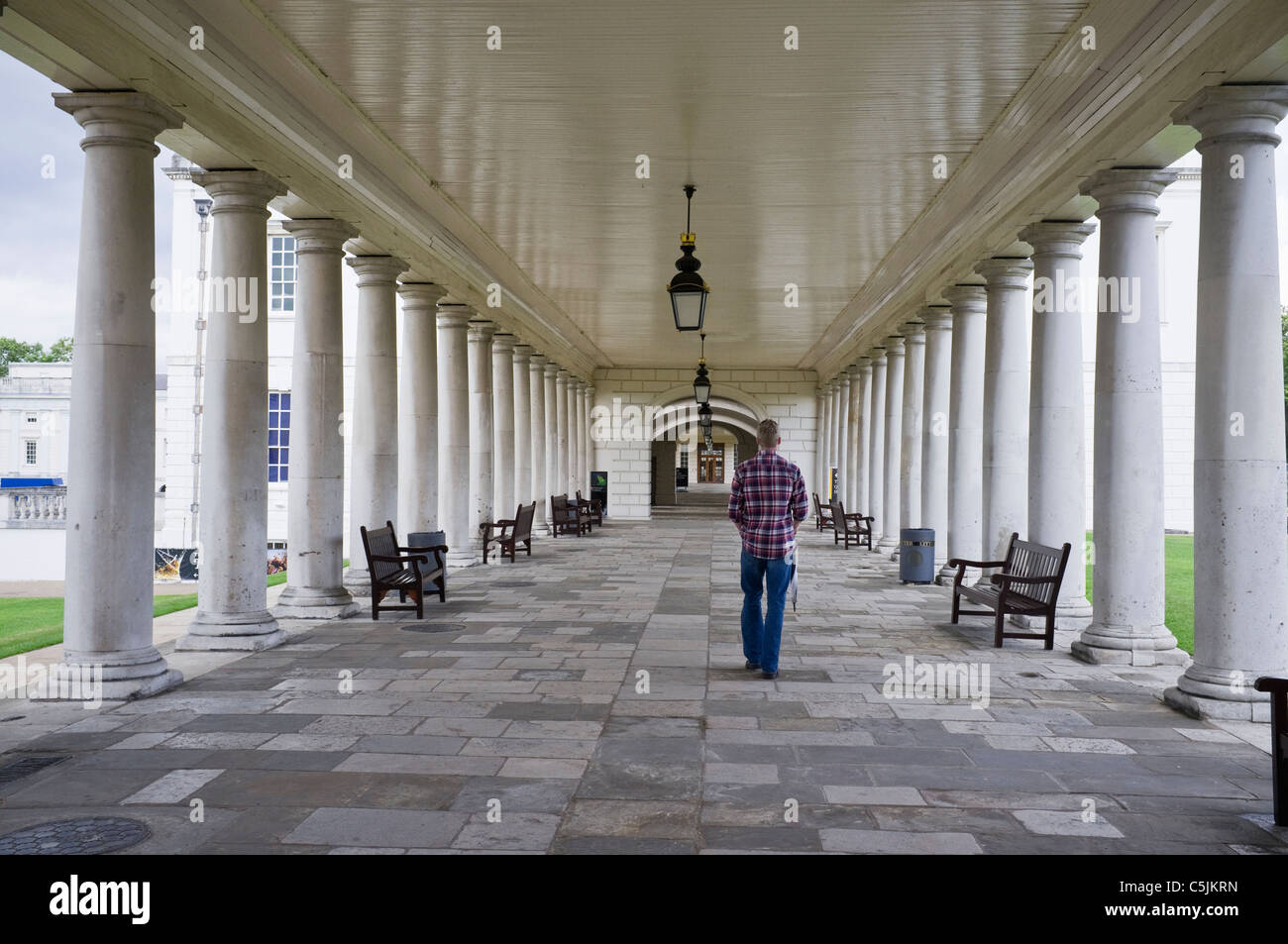 Greenwich, London, England, Regno Unito, Gran Bretagna. Uomo che cammina attraverso il Museo Nazionale Marittimo colonnato della casa della regina Foto Stock