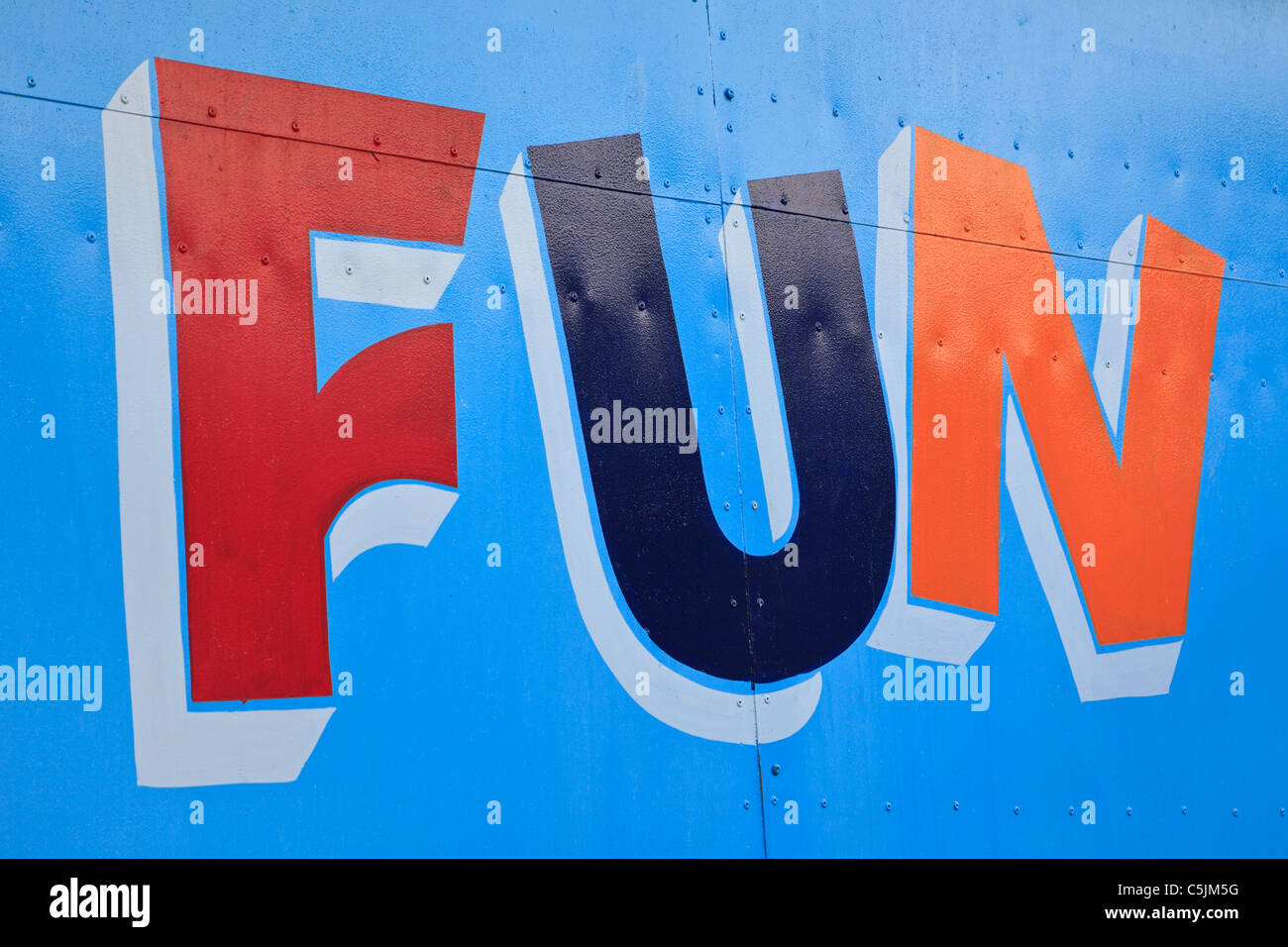 La parola divertimento dipinte in colori luminosi su una porta blu Foto Stock
