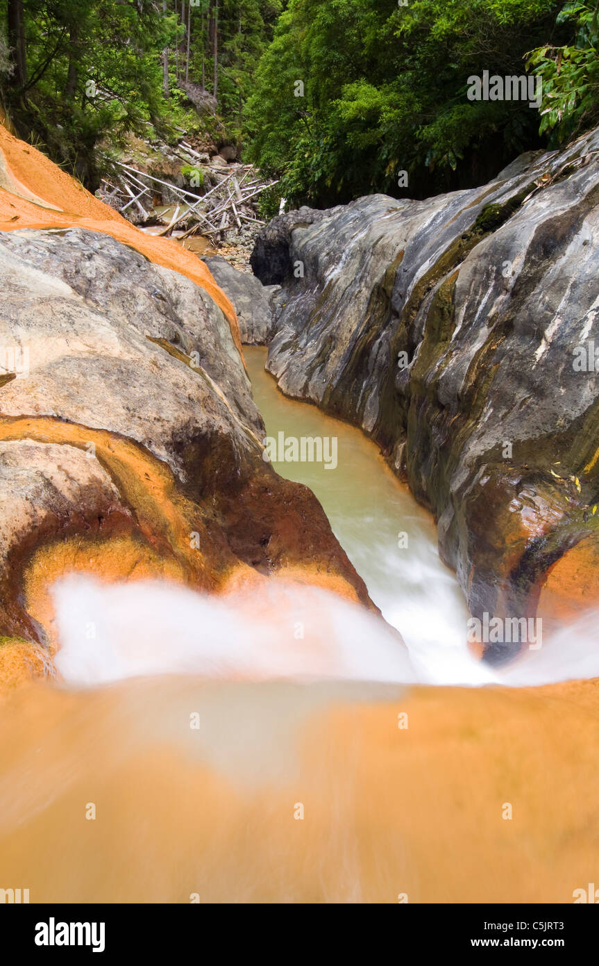 In cima alla cascata di Lombadas, città di Ribeira grande, isola di St Michaels, Azzorre, Portogallo. Ruscello ricco di ferro con acqua di colore arancio che scorre. Foto Stock