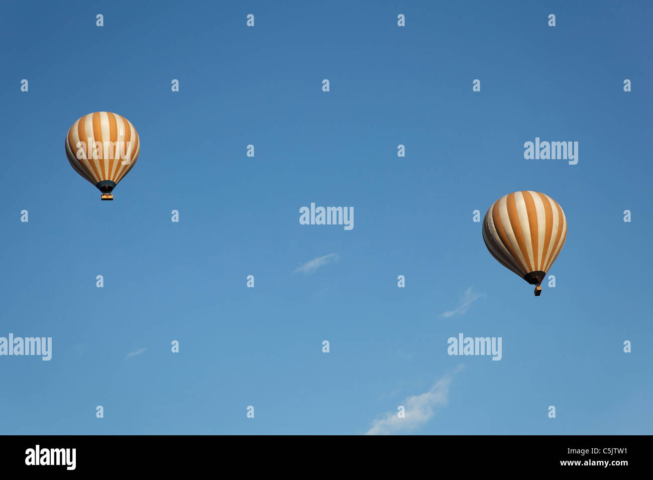 Due di crema e bianco strisce verticali i palloni ad aria calda floating wispy nubi in un cielo blu, paesaggio, copia Spazio, area di ritaglio Foto Stock