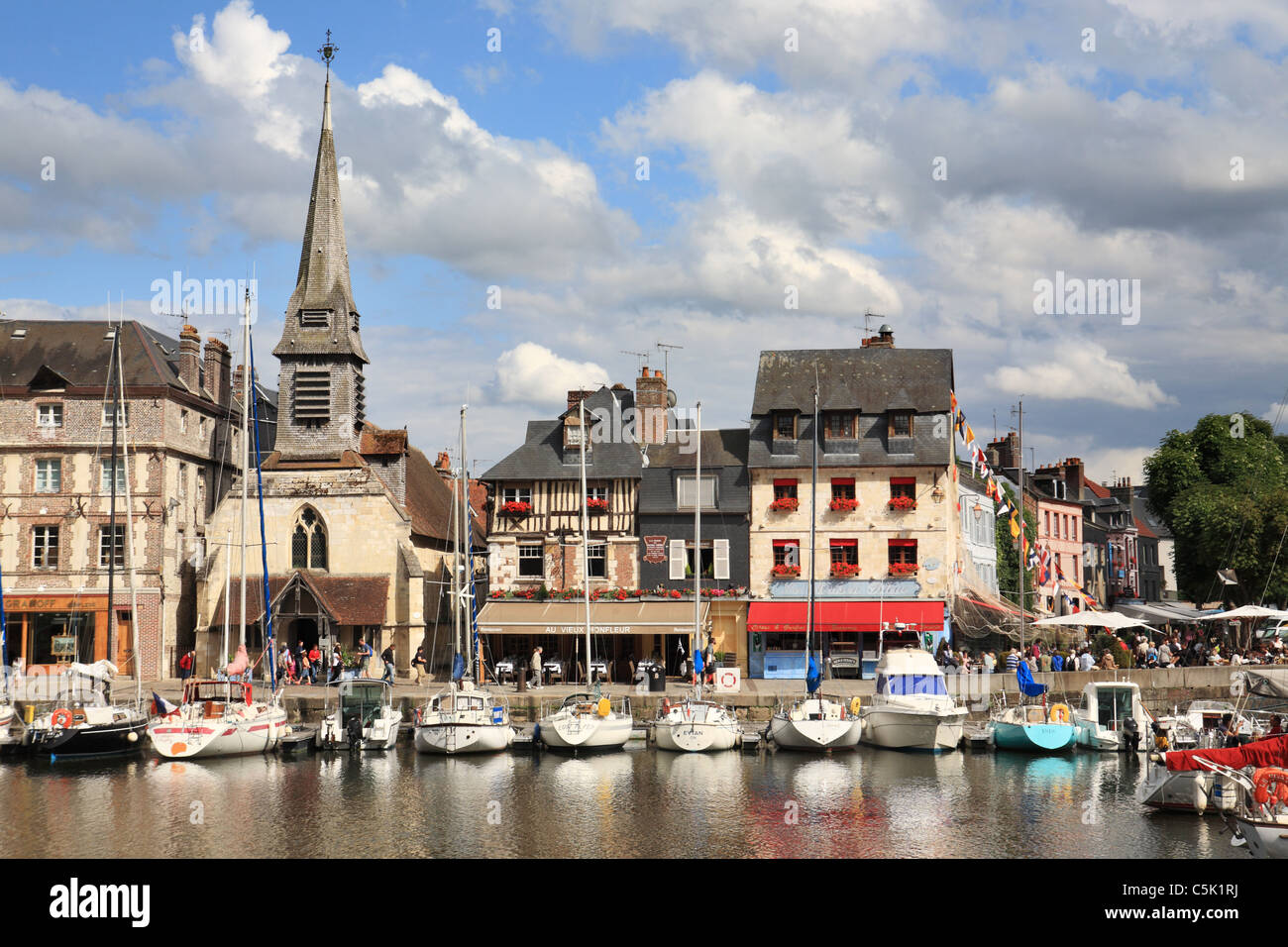 La chiesa e gli edifici storici lungo il Quai St Etienne con yacht ormeggiati in primo piano, Honfleur, Normandia, Francia Foto Stock