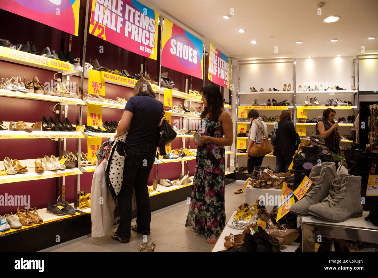 Le donne lo shopping per le scarpe nel prossimo negozio calzatura vendita, London REGNO UNITO Foto Stock