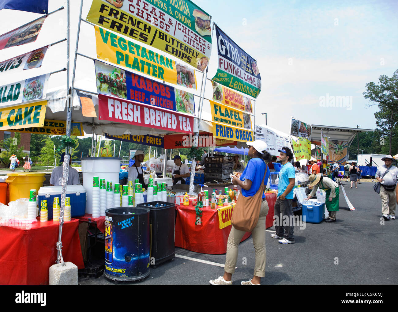 Le persone che visualizzano le selezioni in un grande cibo stallo a un festival all'aperto Foto Stock