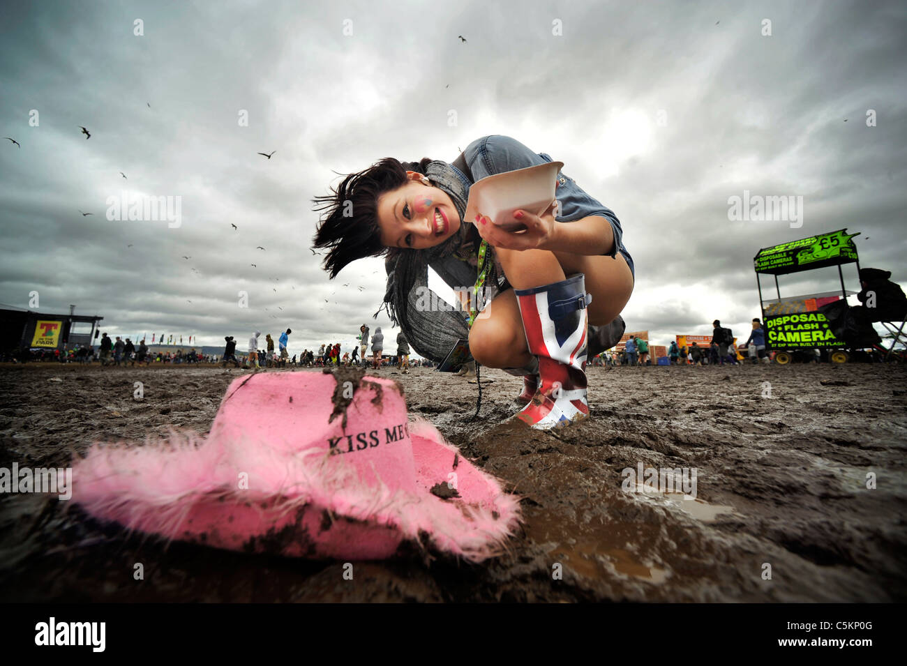 Festival femminile goer scende il suo cappello nel fango . Foto Stock