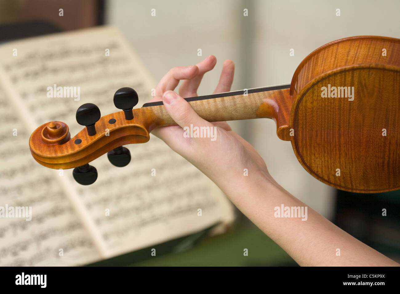 Mano sinistra e il braccio della giovane donna riproduzione di un violino,  spartito musicale stampato in background Foto stock - Alamy