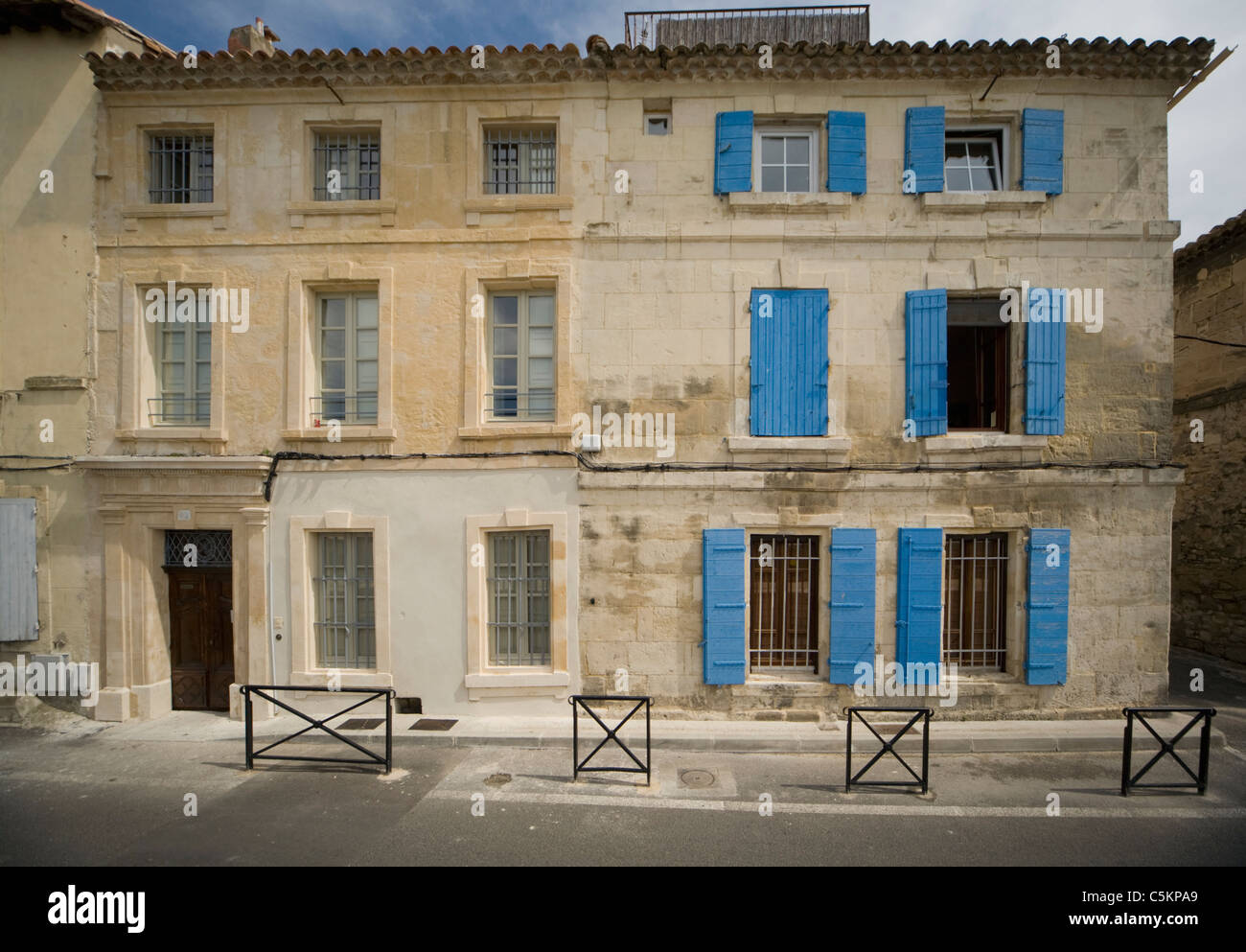 Due contigue antica pietra a 3 piani di case in Arles, Francia, uno con persiane blu su windows Foto Stock