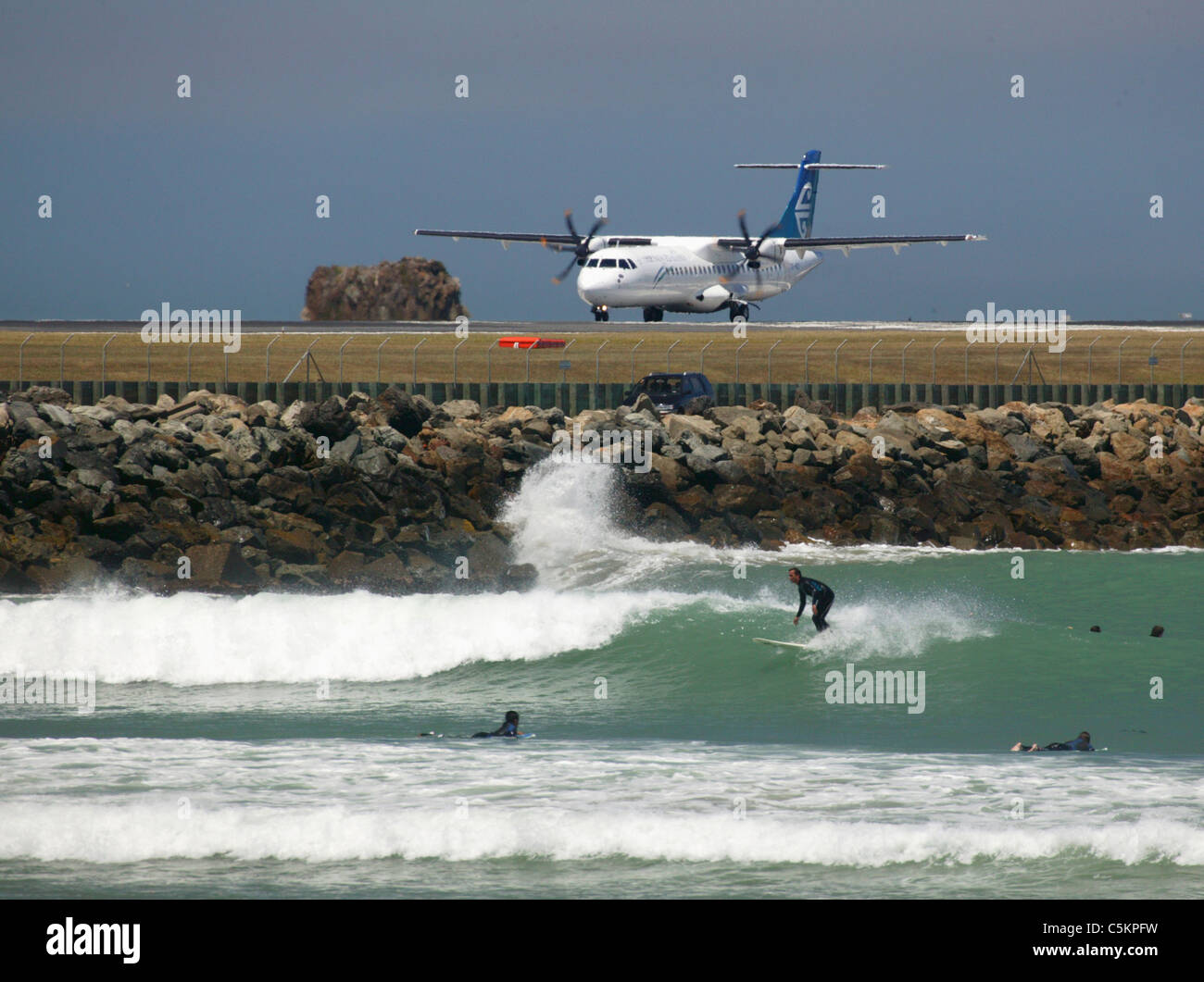 ATR-72 aereo di linea della Air New Zealand sulla pista di aeroporto di Wellington con surfers in Lyall Bay in primo piano Foto Stock