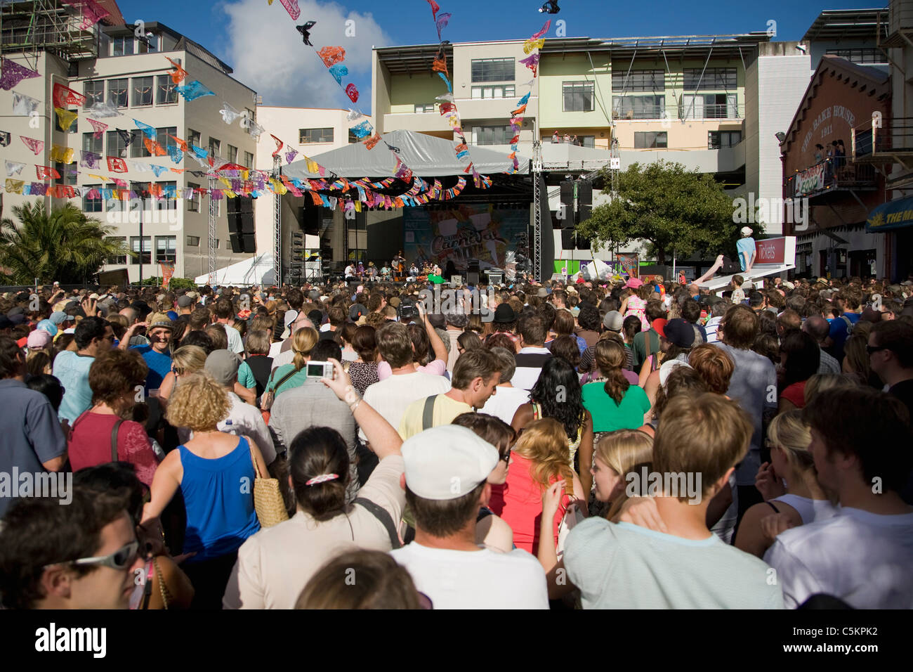 La folla di persone che guardano una banda eseguire su un palcoscenico all'aperto a una fiera di strada, Cuba Street, Wellington, Nuova Zelanda Foto Stock