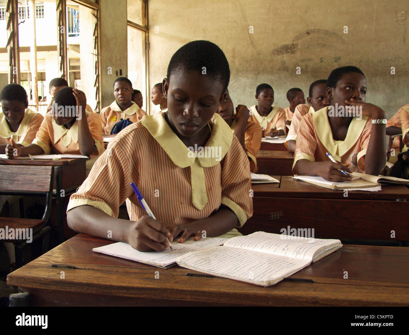 Lagos, Nigeria: Teenage studentessa seduti ad una scrivania in una classe di una scuola pubblica. Gli studenti di indossare un uniforme. Foto Stock