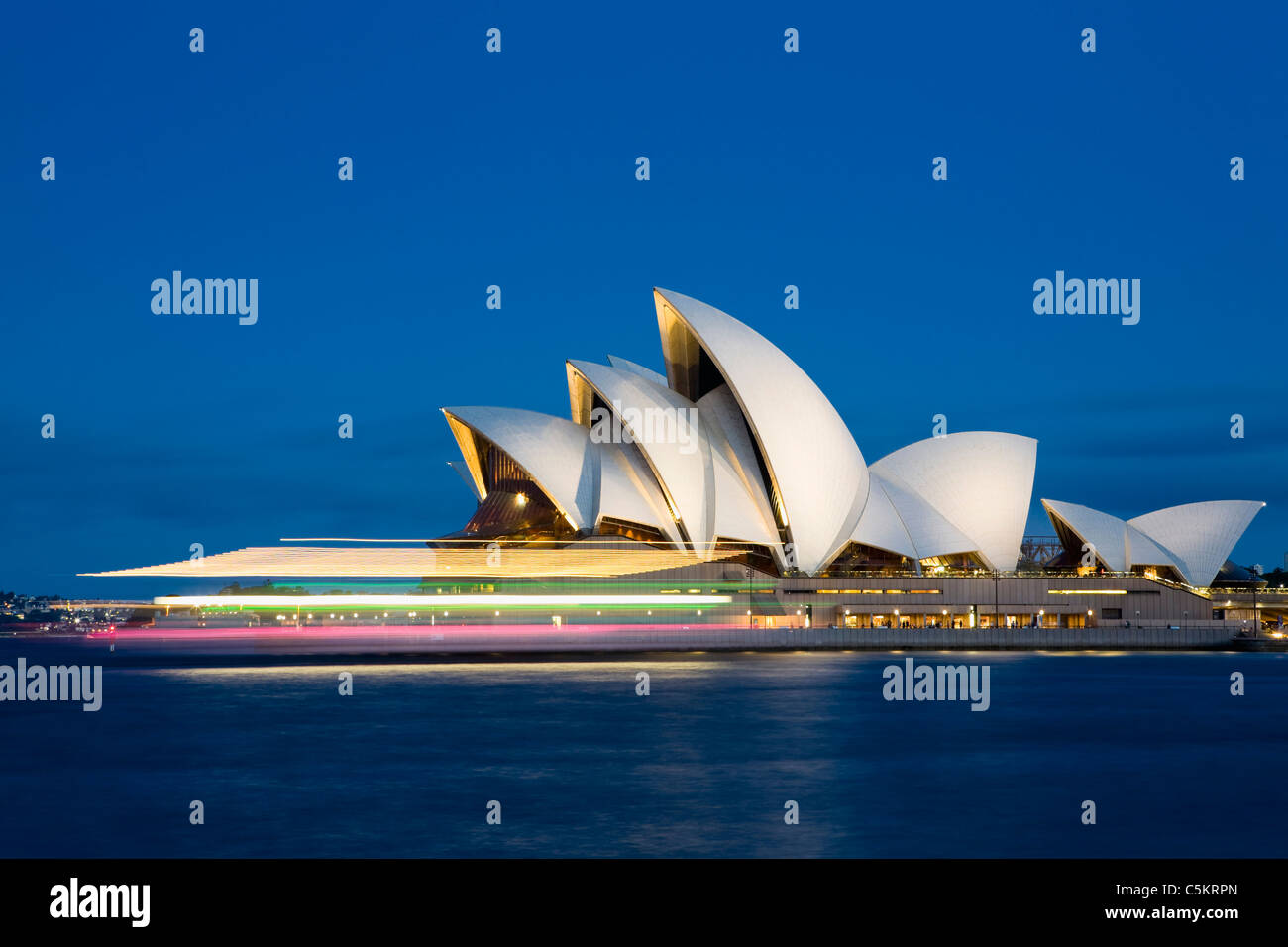 Luci del traghetto blur come passa dall'Opera House al tramonto, Porto di Sydney, Circular Quay, Sydney, Australia. Foto Stock