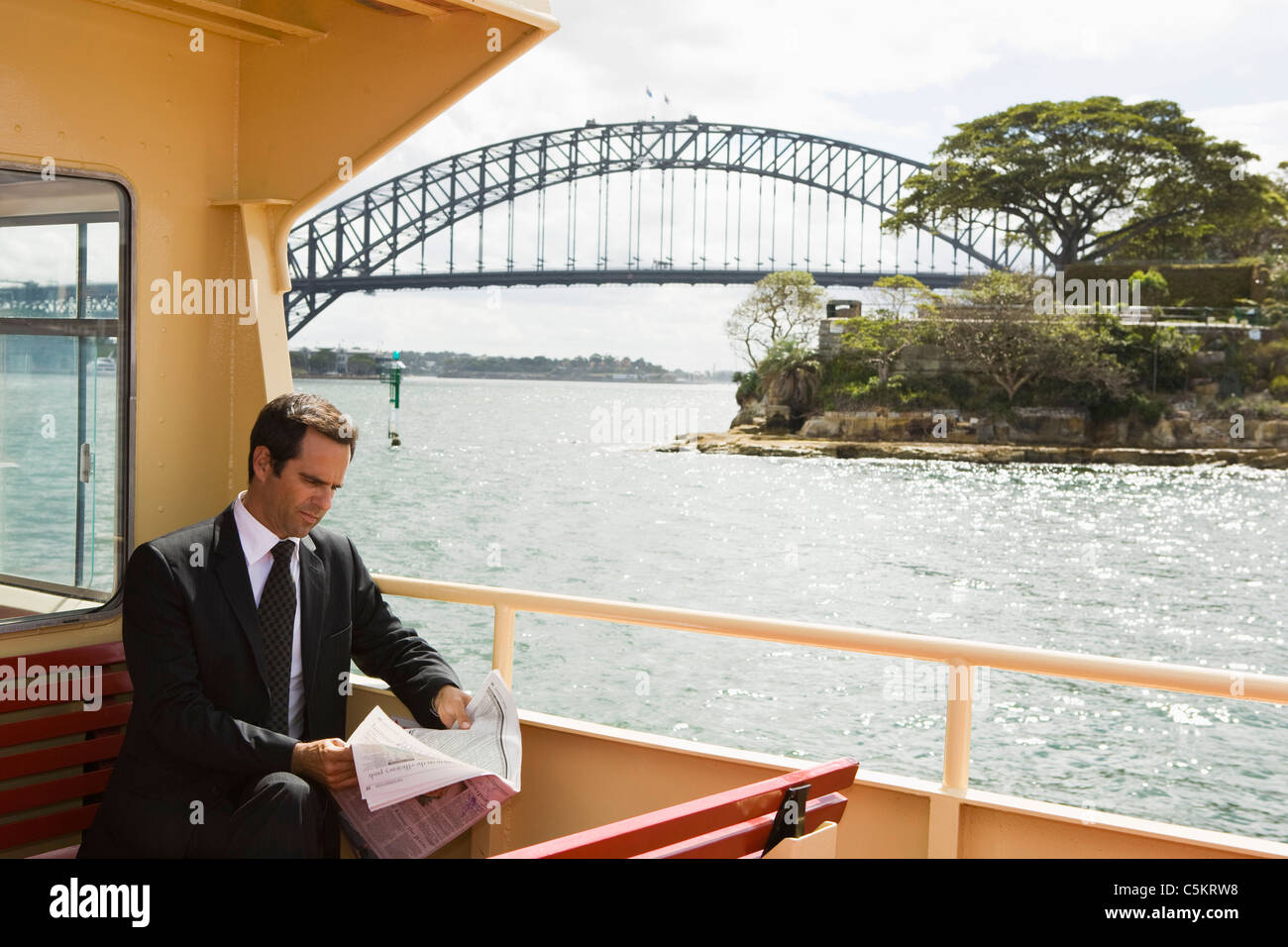 Signor imprenditore lettura sulla barca in porto, Sydney, Australia Foto Stock