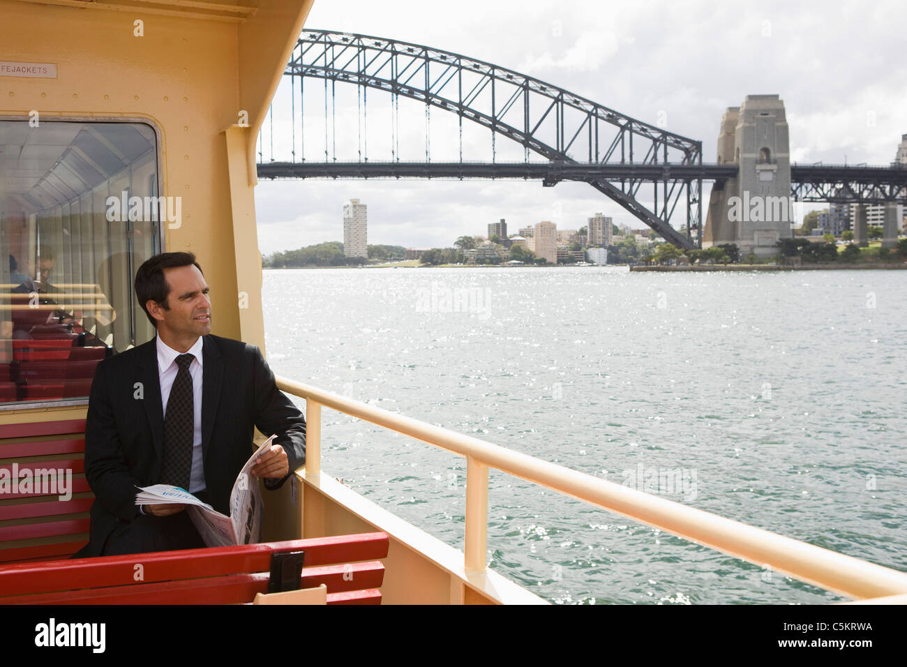 Signor uomo lettura sulla barca vicino al Ponte del Porto di Sydney, Sydney, Australia. Foto Stock