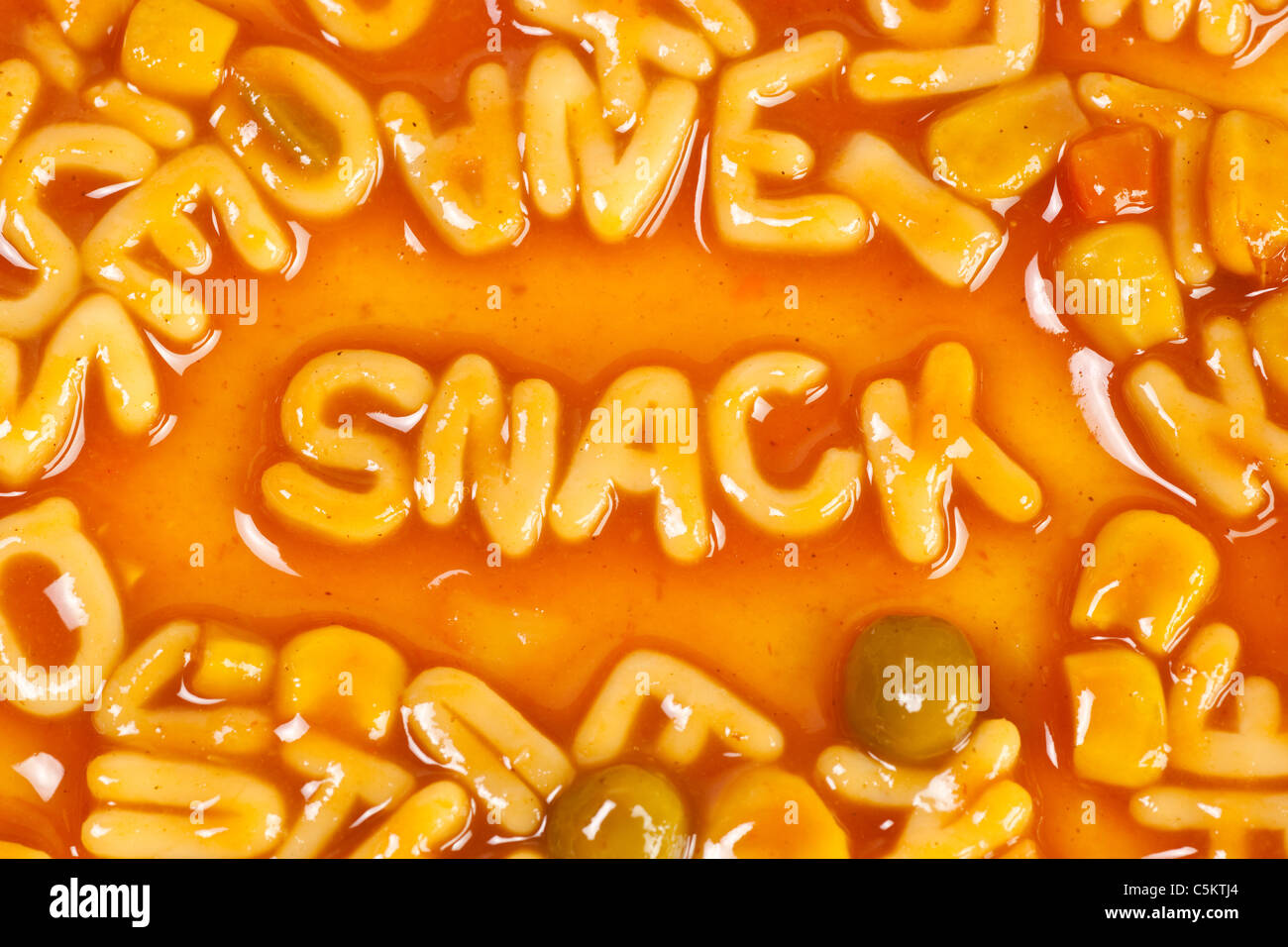 Alfabeto pasta sagomato formante la parola snack in salsa di pomodoro Foto Stock