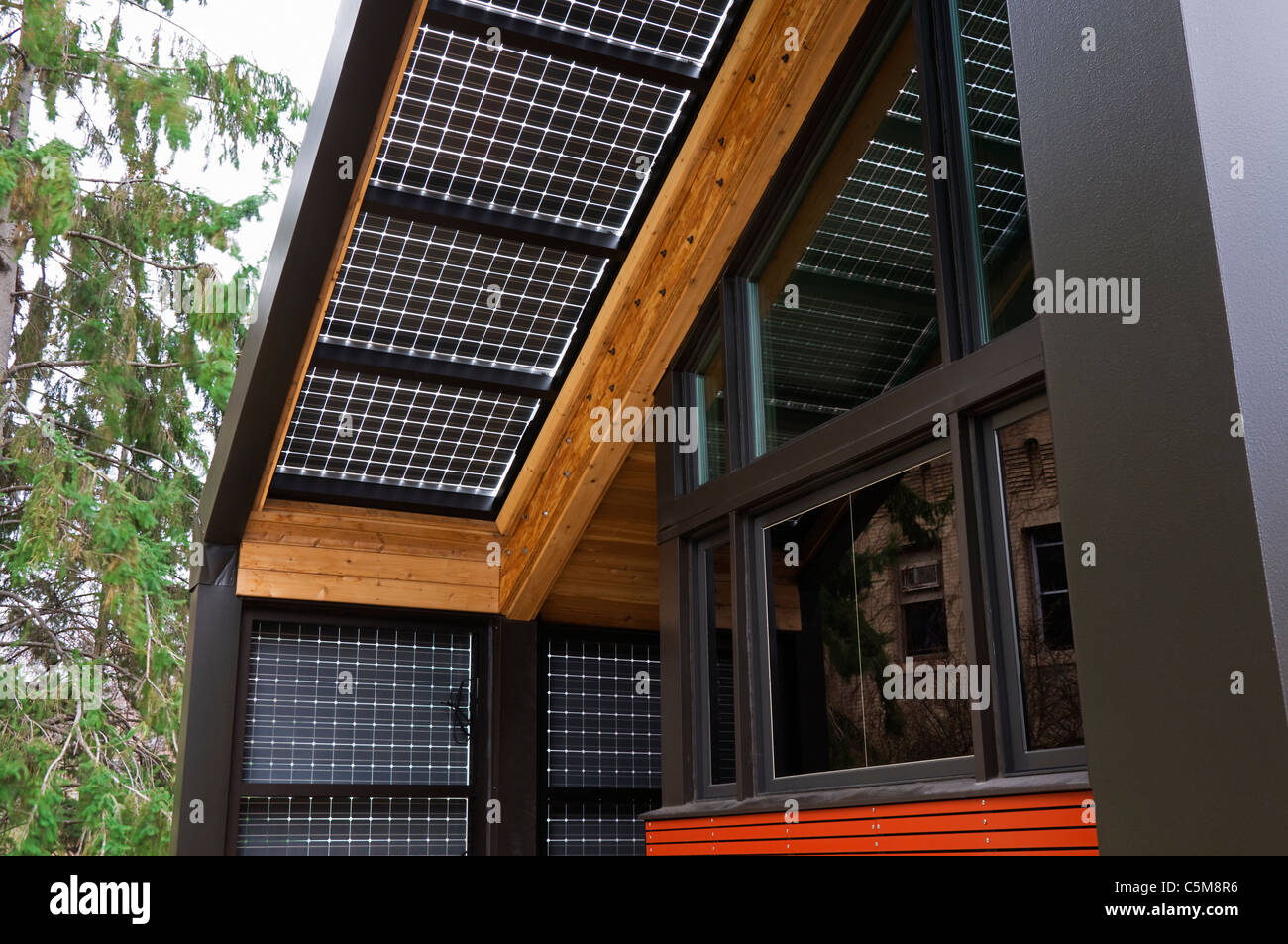 Fonti di energia rinnovabili casa costruita con energia solare che mostra la tecnologia dei pannelli fotovoltaici di gronda e pareti oltre il portico Foto Stock