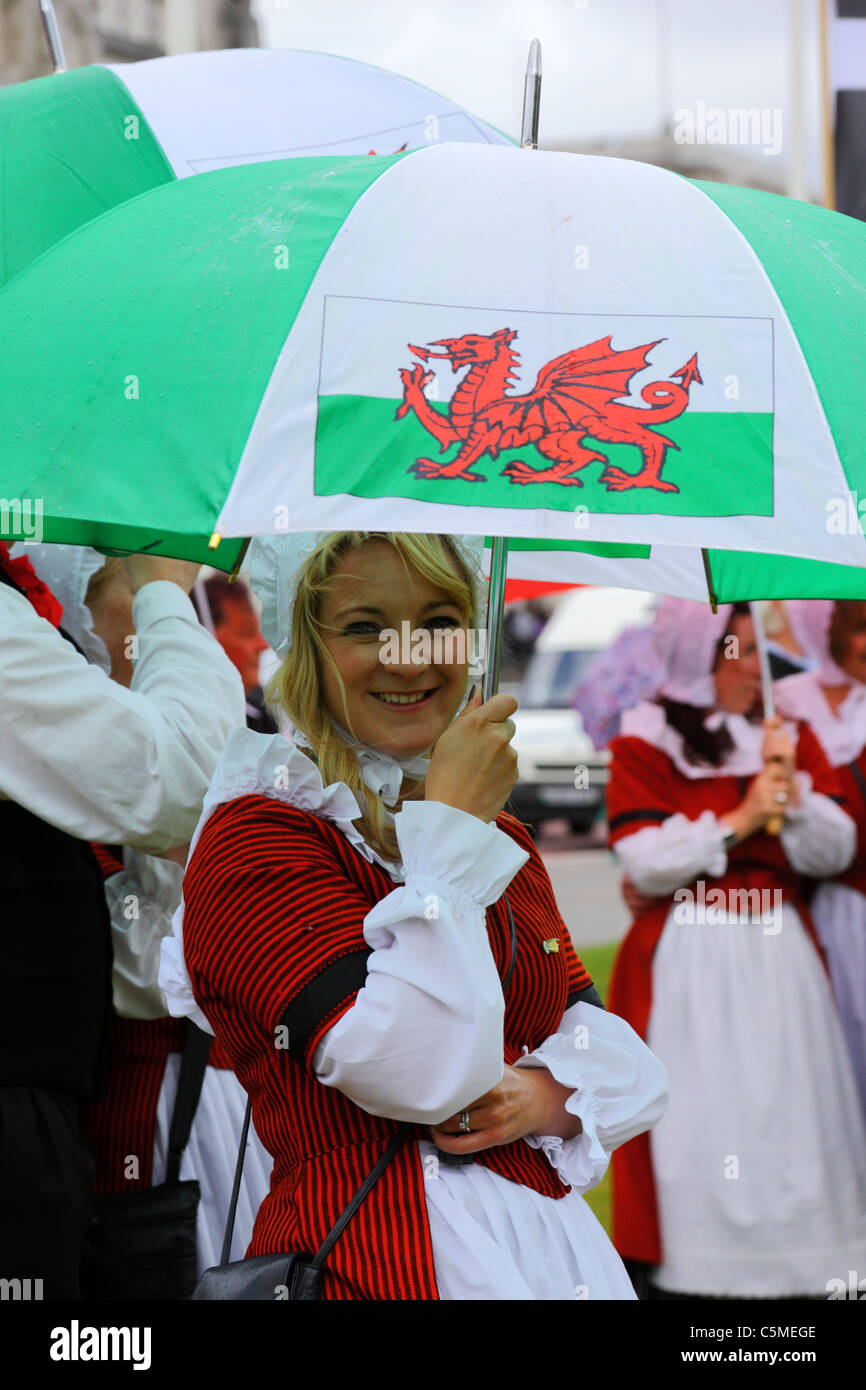 Ragazza in abito tradizionale ripari sotto ombrellone in giornata Midsummers, Cathays Park, Cardiff, South Glamorgan, Wales, Regno Unito Foto Stock