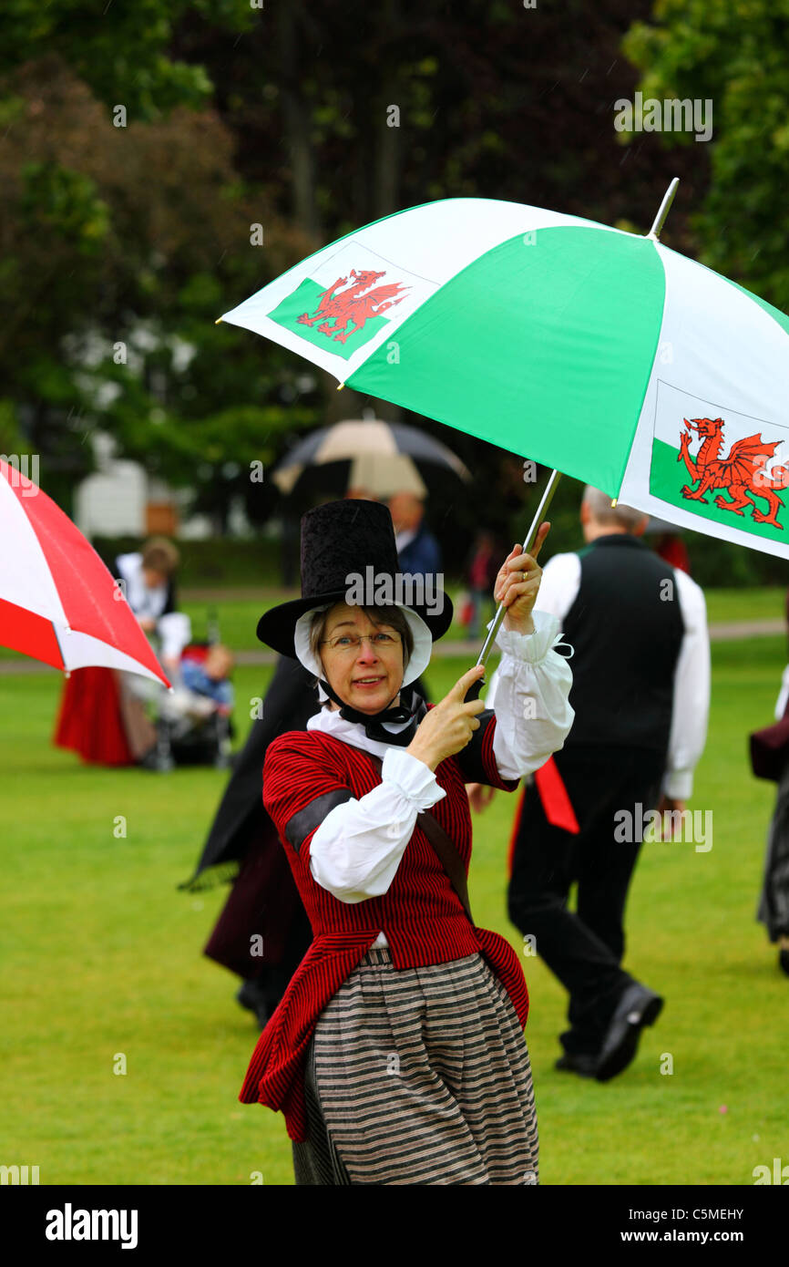 Signora in abito tradizionale ballo sotto ombrellone in giornata Midsummers, Cathays Park, Cardiff, South Glamorgan, Wales, Regno Unito Foto Stock