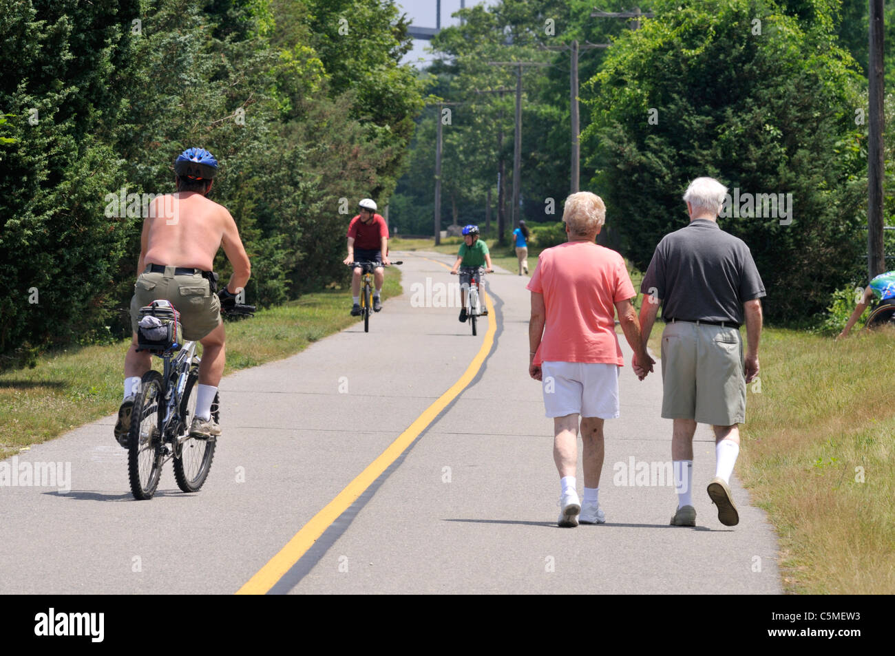 Coppia di anziani tenendo le mani a piedi lungo una pista ciclabile in estate su una soleggiata cielo blu al giorno. Stati Uniti d'America Foto Stock