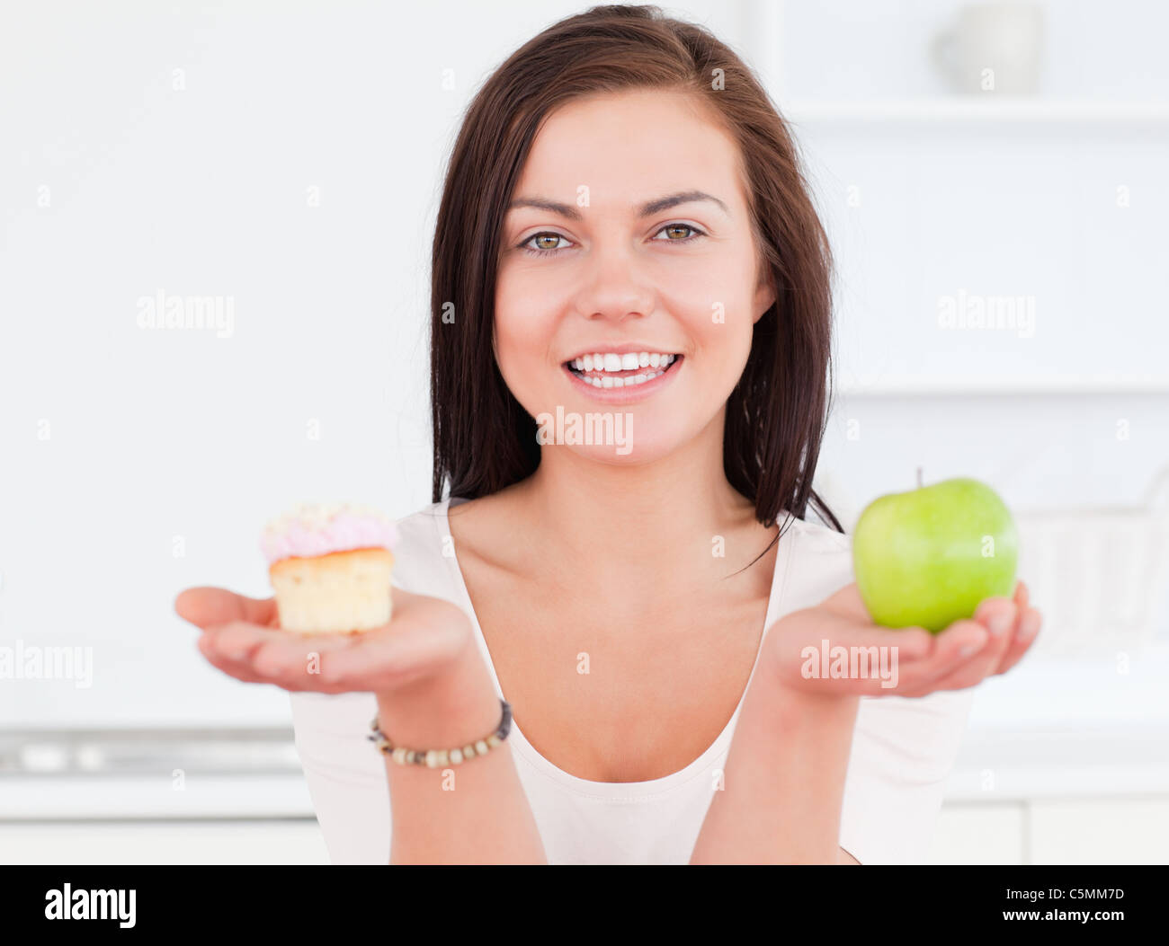 Giovane donna con una mela e un pezzo di torta Foto Stock