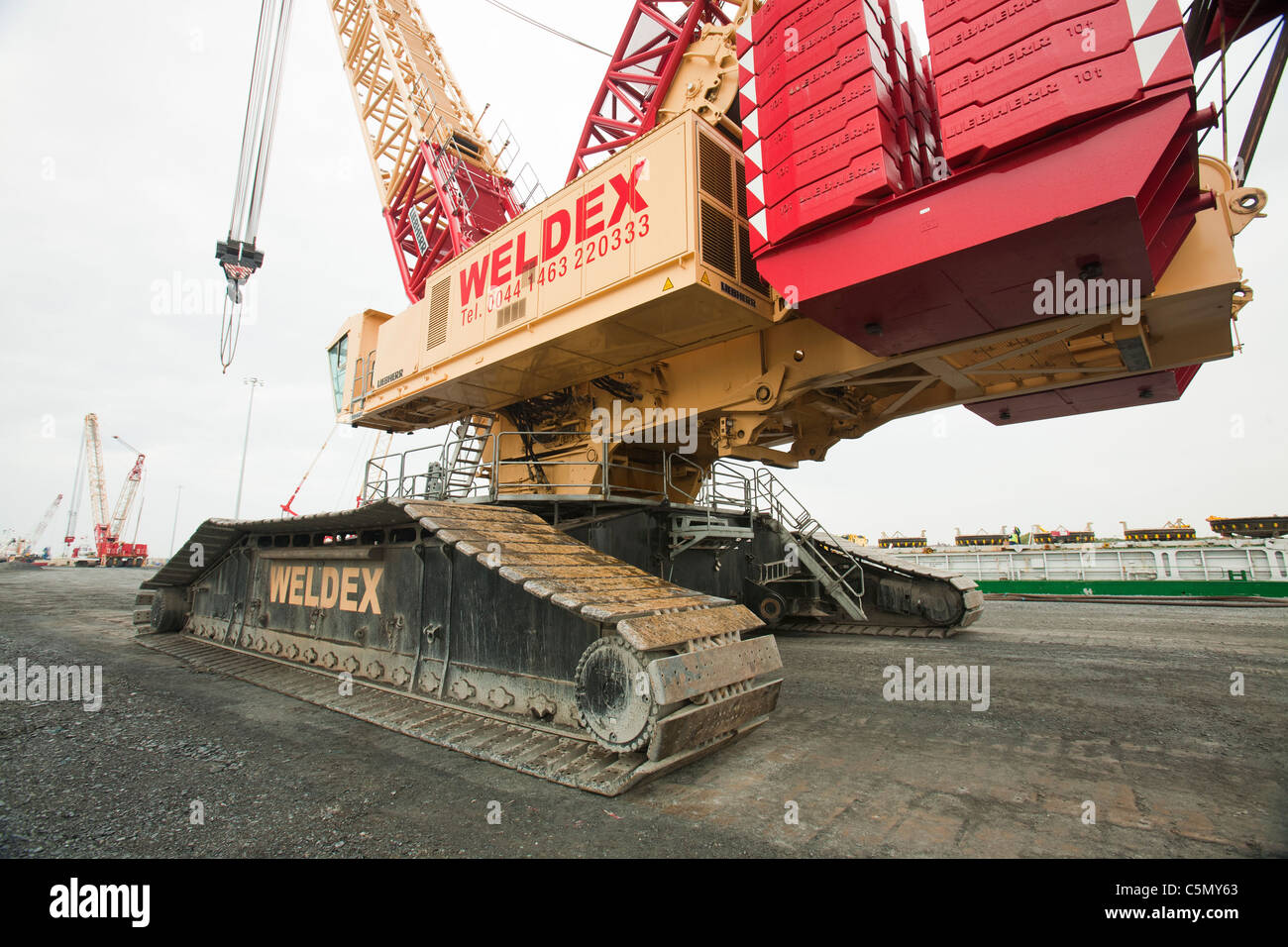 Un enorme gru essendo utilizzato per caricare pices per la Walney offshore wind farm presso il molo di Barrow in Furness, Cumbria, Regno Unito. Foto Stock