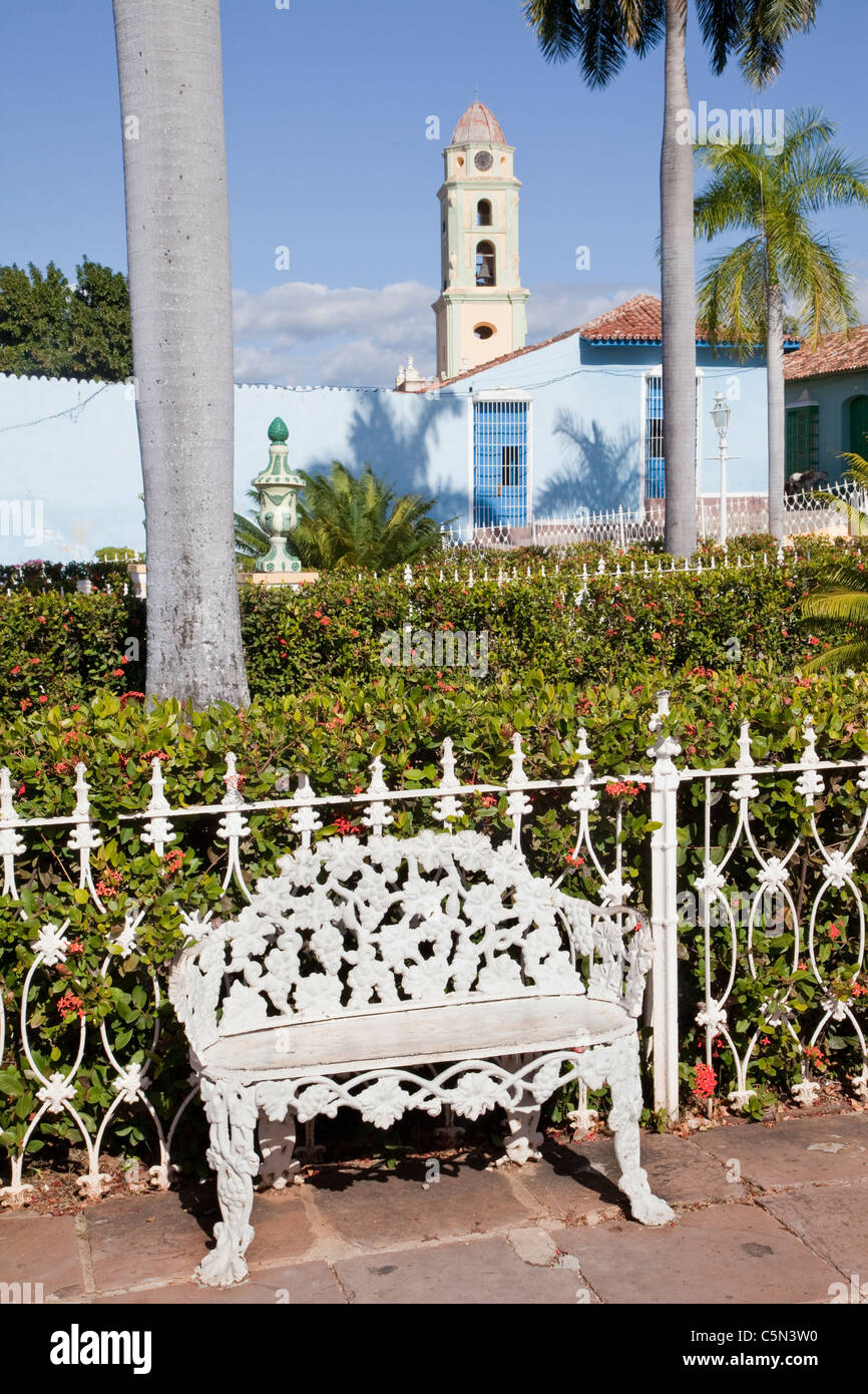 Cuba Trinidad. Ferro battuto sedia in Plaza de Armas. Il campanile della chiesa e convento di San Francisco nella parte posteriore. Foto Stock