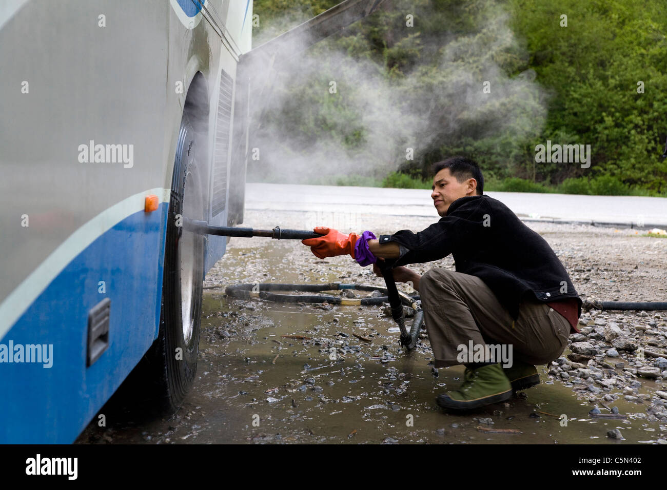 Conducente di un cinese a lunga distanza coach raffredda il più riscaldata freni con tubo flessibile per acqua / la rondella a pressione, creando vapore. Cina. Foto Stock