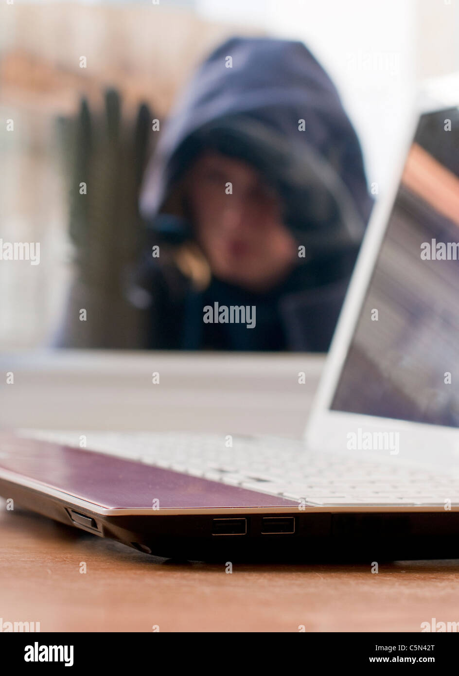 Un ladro cercando di penetrare in una casa per rubare un computer portatile Foto Stock